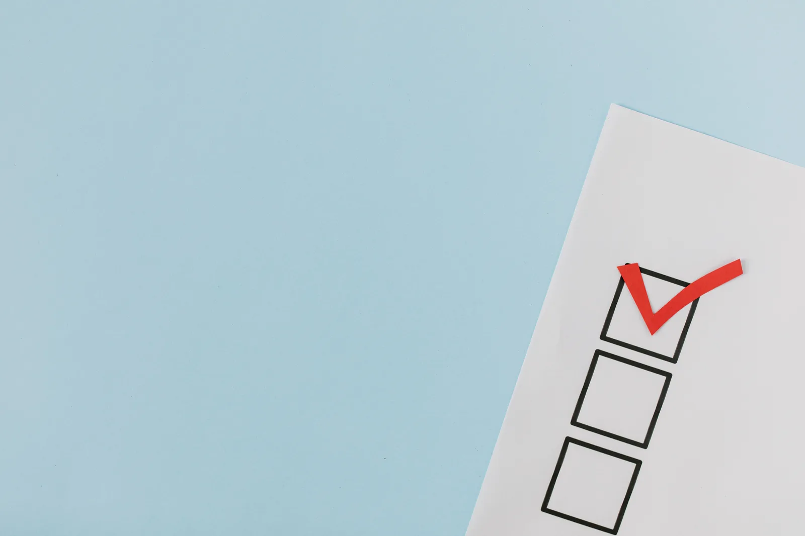 A checklist with a red checkmark symbolizing a completed task on a pastel blue background. How Small Businesses Should Approach Email Marketing