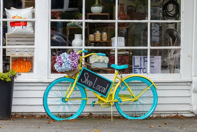A colorful bicycle with flowers and 'Shop Local' sign outside a store in Sudbury, MA. Small Business Marketing Strategy: 2027 Guide