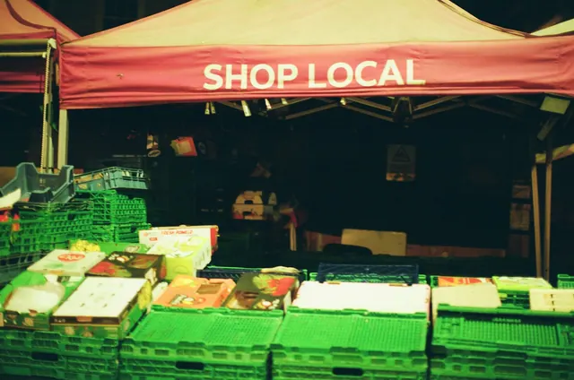 Market stall with 'shop local' banner and fresh produce. Small Business Social Media Plan: 2027 Guide