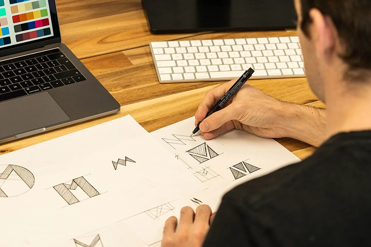 Designer sketching several possible business logo concepts on paper.